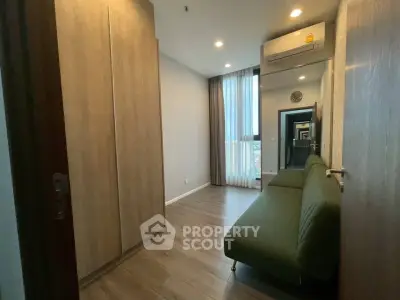 Modern apartment interior with sleek wooden flooring and stylish green sofa, featuring ample natural light.