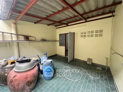 Spacious utility area with tiled flooring and storage containers
