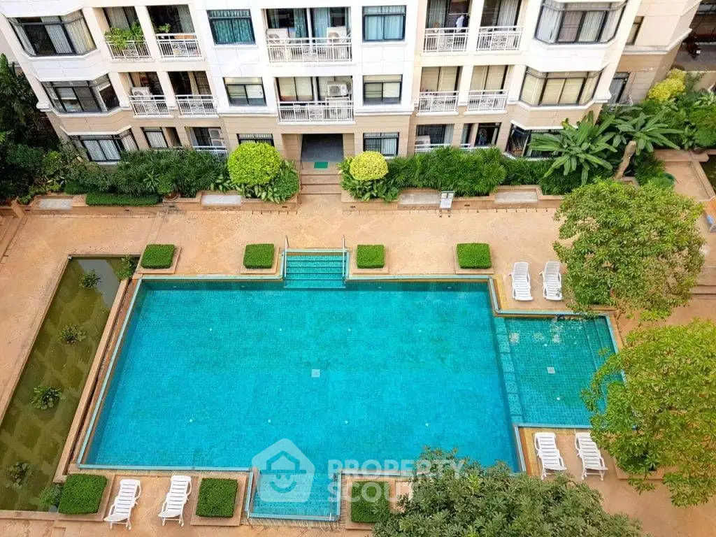 Luxurious apartment building with stunning pool and lush greenery, perfect for relaxation and leisure.