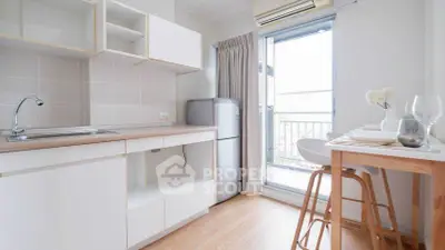 Modern kitchen with open layout and balcony access, featuring sleek cabinetry and natural light.