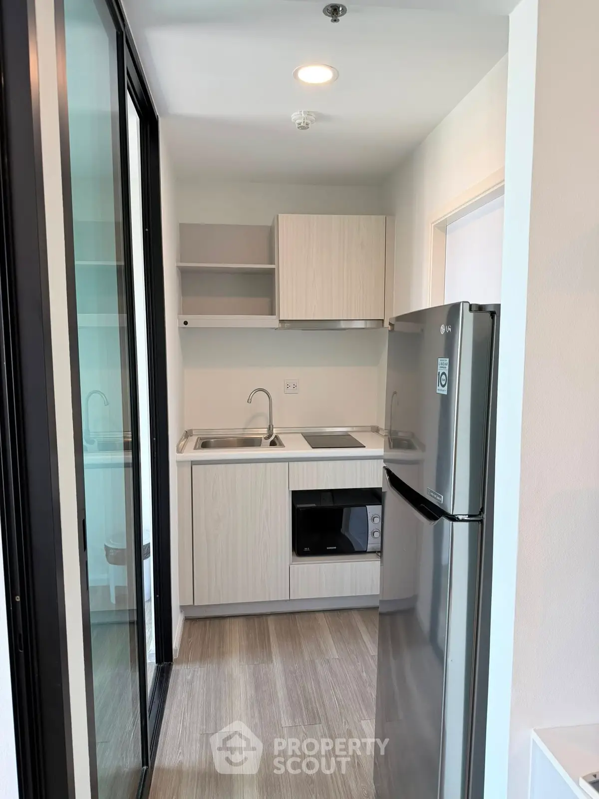 Modern compact kitchen with sleek appliances and stylish cabinetry in a contemporary apartment.
