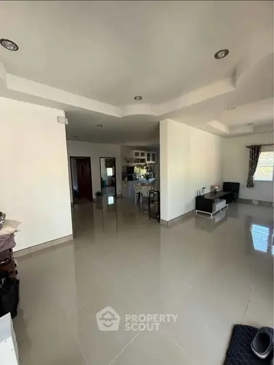 Spacious open-plan living room with modern kitchen and ample natural light