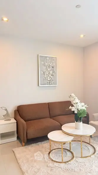 Elegant living room with brown sofa, stylish coffee tables, and modern decor in a cozy apartment.