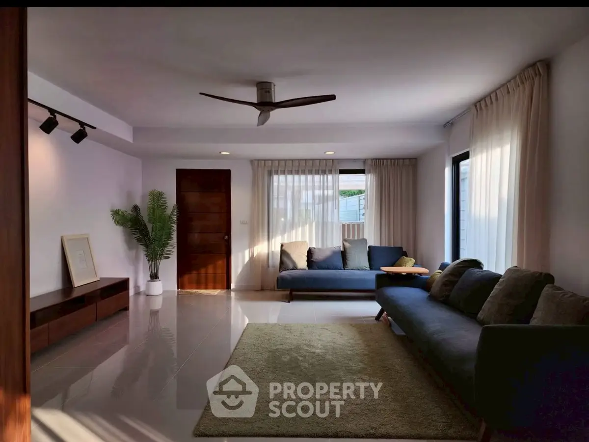 Spacious living room with modern decor, large windows, and cozy seating area.