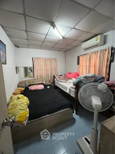 Cozy bedroom with twin beds, air conditioning, and natural light from windows.