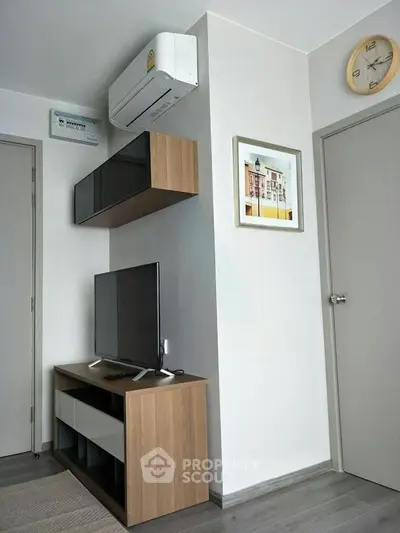 Modern living room with sleek TV stand, wall-mounted shelves, and air conditioning unit.