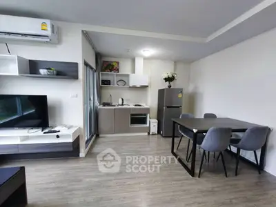 Modern open-plan living room with sleek kitchen and dining area, featuring contemporary furniture and appliances.