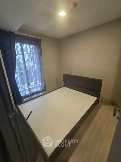 Modern bedroom with large window and stylish bed frame in a cozy apartment.