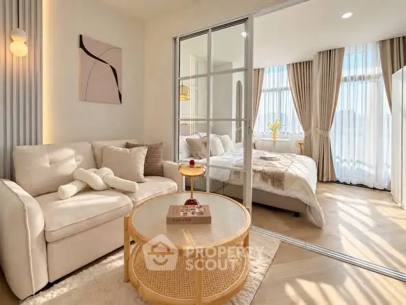 Chic modern living room with cozy sofa and elegant bedroom view through glass partition.