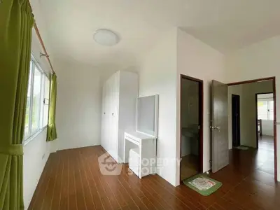Spacious bedroom with wooden flooring and ample natural light