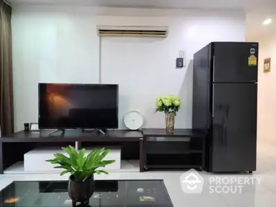 Spacious and modern living room with glossy tiled flooring, featuring a large refrigerator, sleek TV setup, and a vibrant potted plant enhancing the room's ambiance.