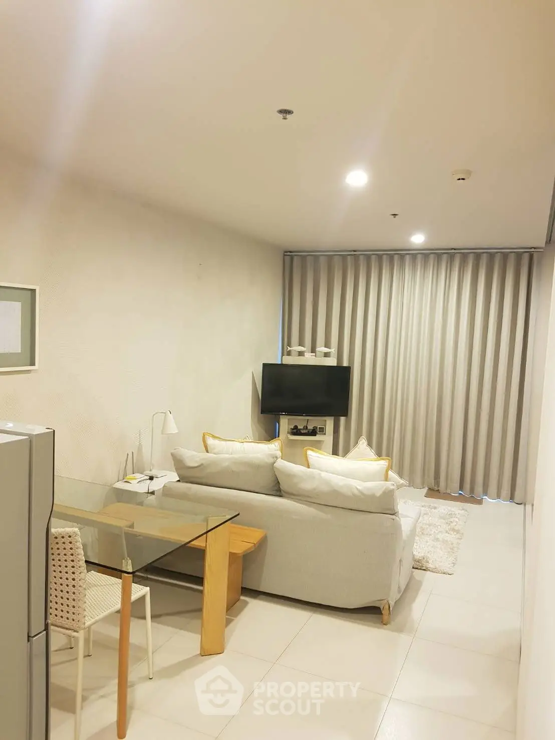 Modern living room with cozy sofa, TV, and dining area in open layout apartment.