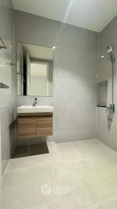 Modern minimalist bathroom with sleek gray tiles and wall-mounted sink.