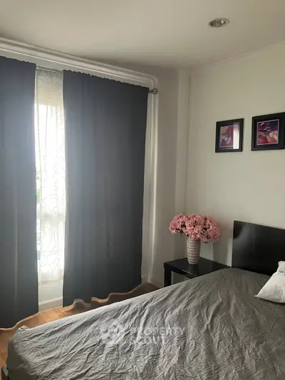 Cozy bedroom with elegant decor, featuring a stylish bed, bedside table with flowers, and soft lighting.
