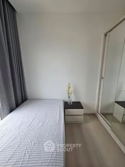 Minimalist bedroom with single bed, mirrored wardrobe, and soft lighting.