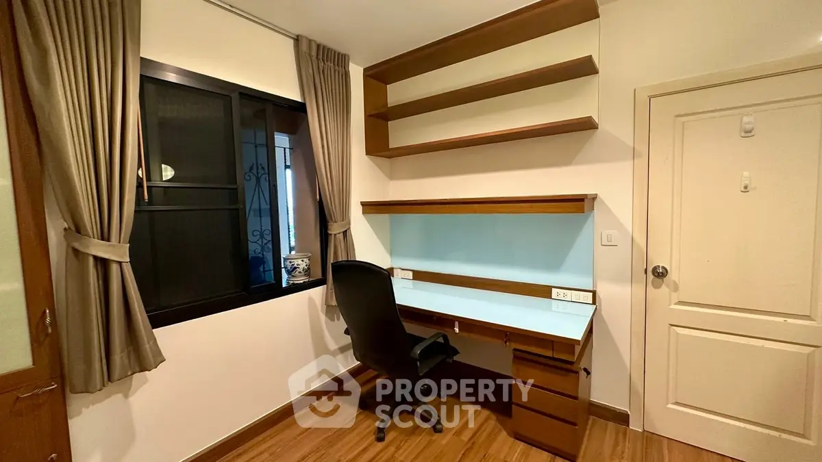 Modern study room with built-in desk and shelves, featuring elegant wood finishes and natural light.