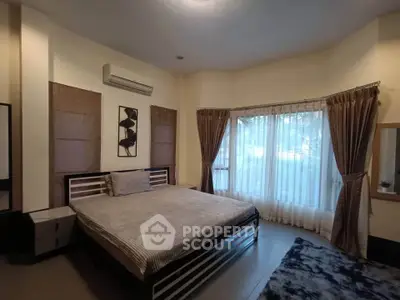 Spacious bedroom with large window and modern decor in a cozy real estate listing.