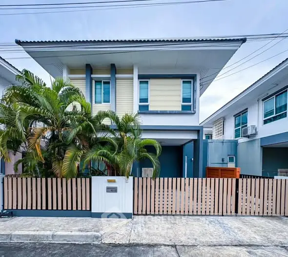 Modern two-story house with a sleek design and lush greenery in a suburban neighborhood.