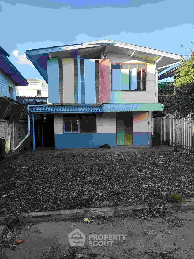Charming two-story house with colorful facade and spacious front yard.