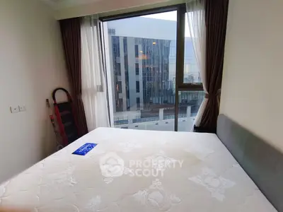 Modern bedroom with large window offering city view, featuring a comfortable bed and elegant curtains.
