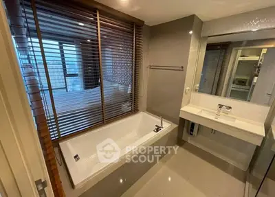 Modern bathroom with sleek bathtub and stylish blinds in luxury apartment.