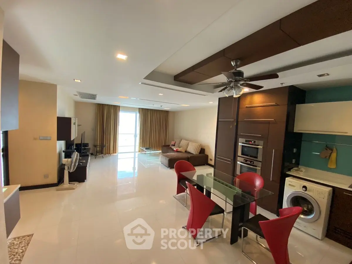 Spacious modern living room with open kitchen, featuring sleek appliances and stylish decor.