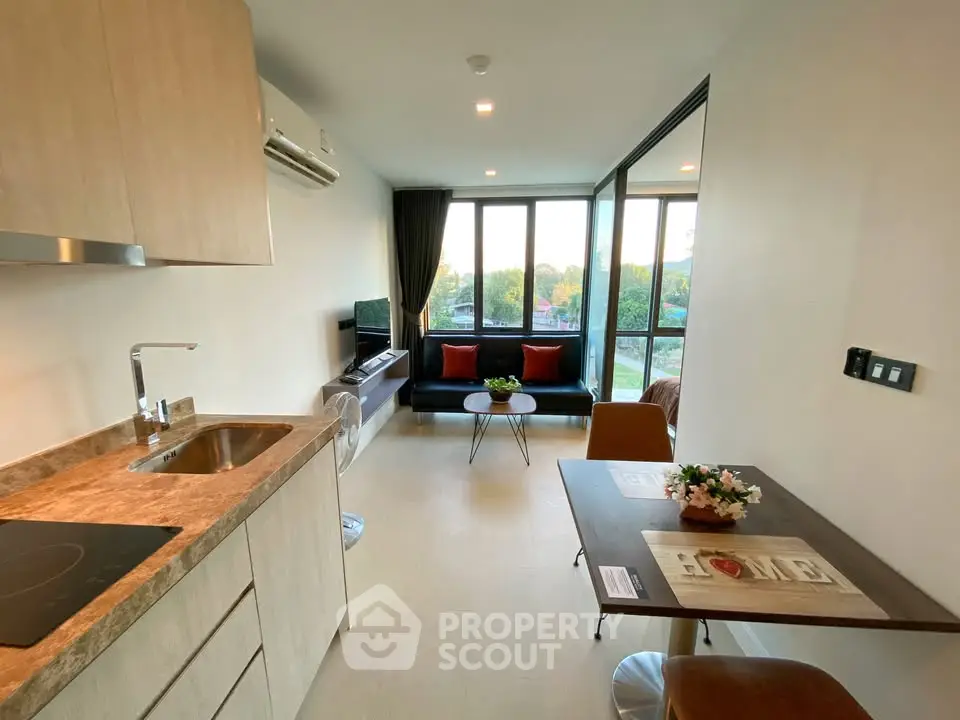 Modern open-layout kitchen and living room with large windows and scenic view.