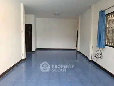 Spacious empty room with blue tiled floor and large window