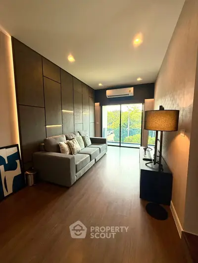 Modern living room with stylish decor and large window offering natural light and garden view.