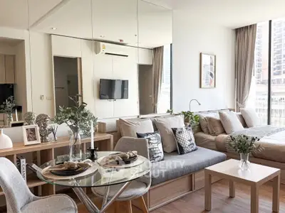 Modern open-plan living room with dining area and large windows in a stylish apartment.