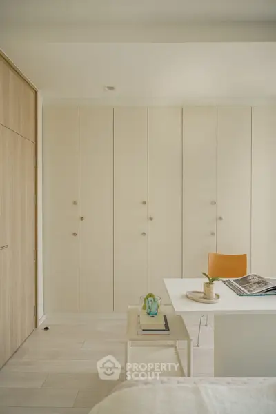 Modern bedroom with minimalist design, featuring built-in wardrobes and a cozy workspace.