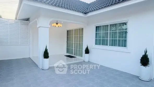 Charming white exterior of a modern home with tiled patio and elegant lighting.