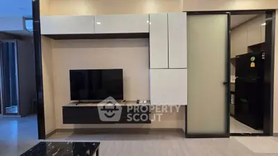 Modern living room with sleek TV unit and sliding door to kitchen