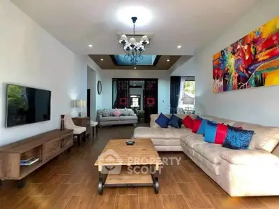 Spacious living room with modern decor and vibrant artwork, featuring a cozy sectional sofa and wooden flooring.