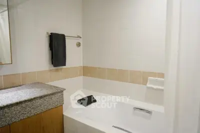 Modern bathroom with sleek bathtub and granite countertop in a stylish real estate property.