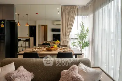 Modern living room with dining area and large windows, featuring cozy decor and abundant natural light.