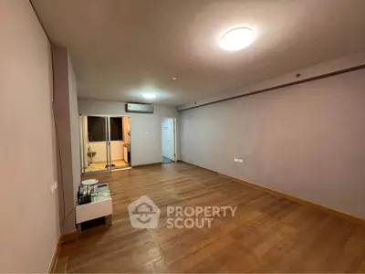 Spacious empty living room with wooden flooring and modern lighting