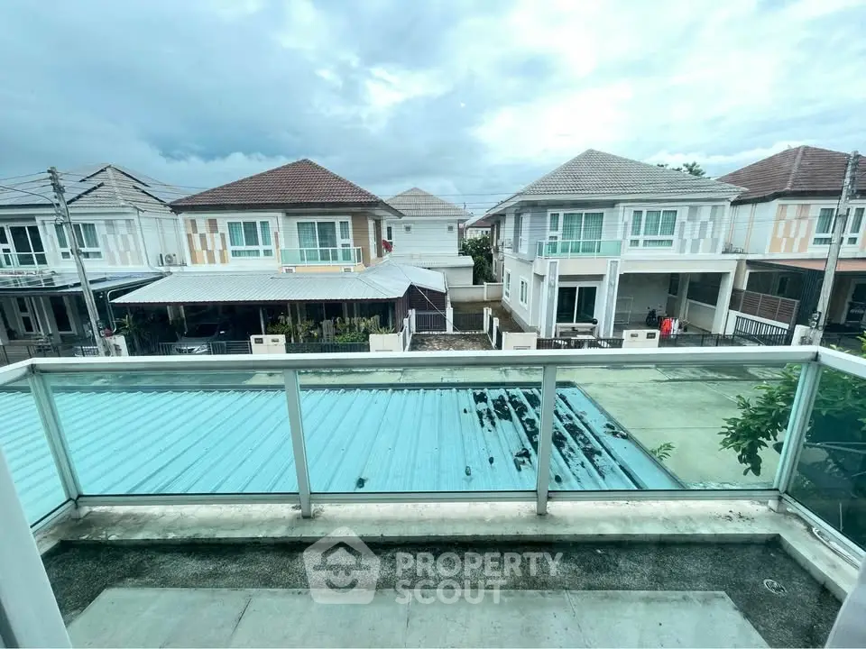 Charming suburban view from a modern balcony overlooking stylish homes with tiled roofs and lush surroundings.