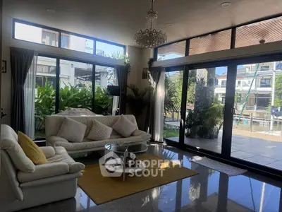 Luxurious living room with large windows and garden view, featuring elegant decor and natural light.