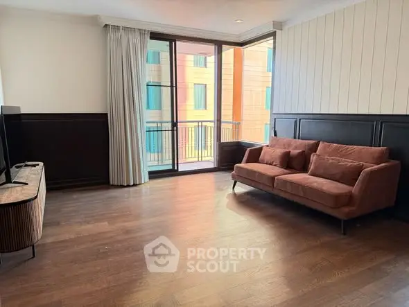 Spacious living room with modern sofa and large windows leading to balcony