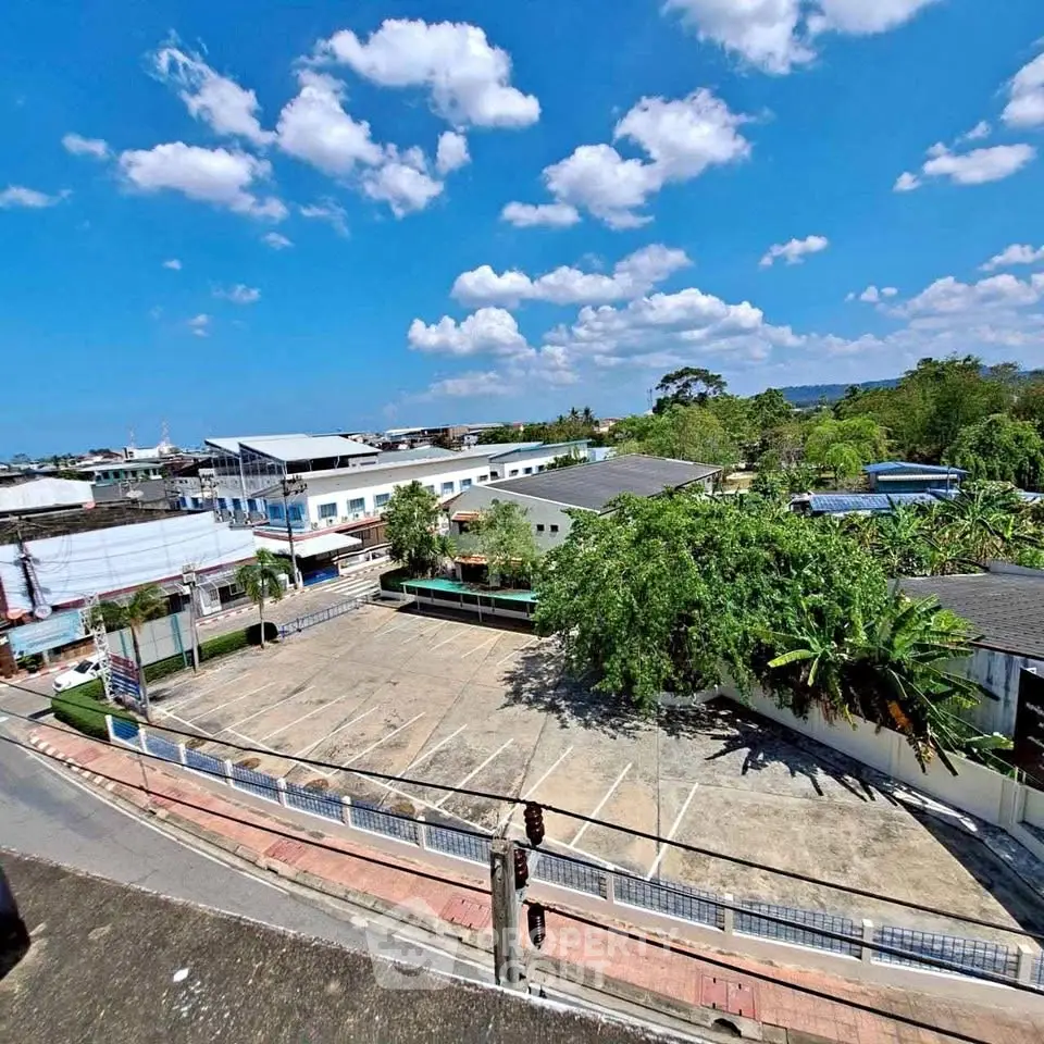 Expansive view of commercial property with ample parking and lush greenery under a bright blue sky.