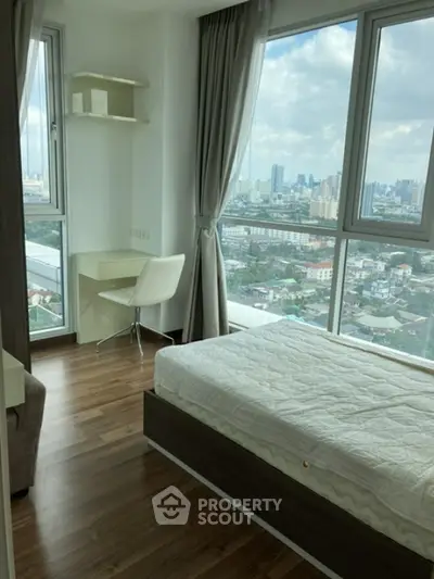 Modern bedroom with city view, featuring large windows and stylish furnishings.