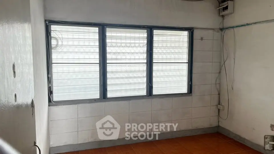 Spacious room with large window and tiled floor, ideal for customization.