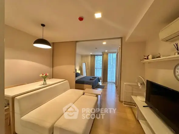 Modern open-plan living room with cozy dining area and stylish bedroom view.