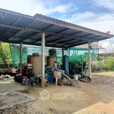 Outdoor storage area with metal roof and various equipment, ideal for utility and organization.
