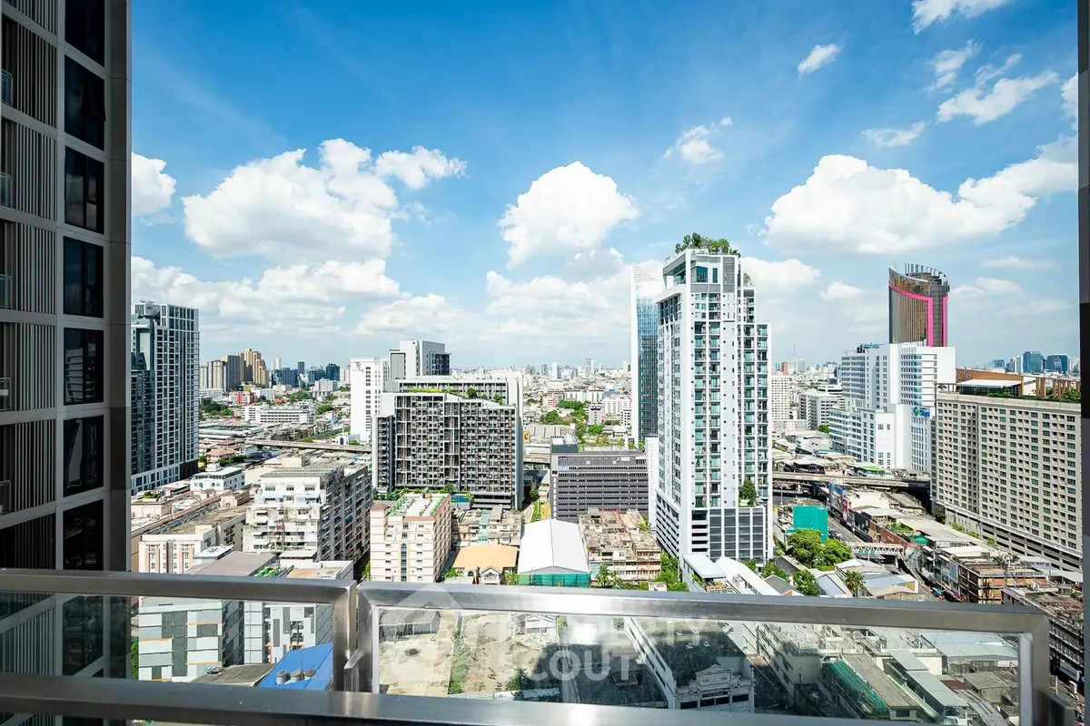 Stunning cityscape view from a high-rise balcony with modern skyscrapers and blue sky.