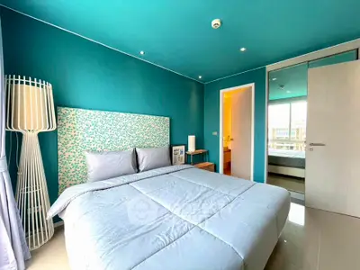 Modern bedroom with teal walls, stylish decor, and ample natural light.