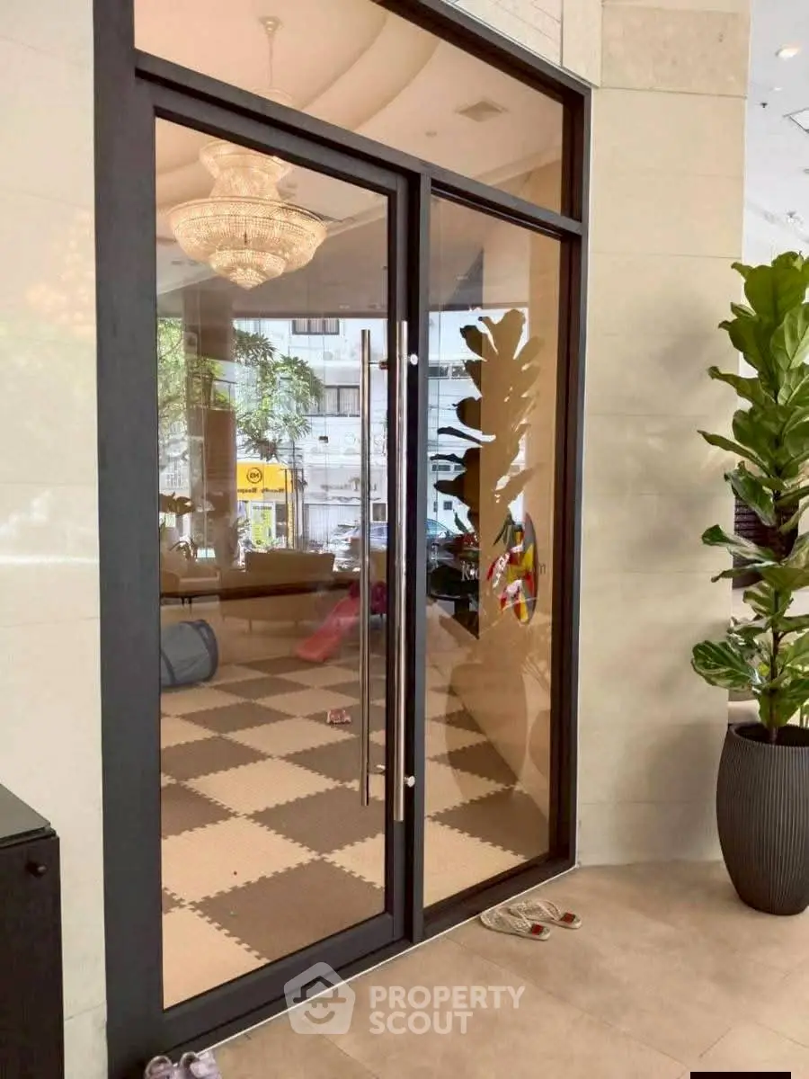 Elegant entrance with glass doors and indoor plants in a modern building lobby.