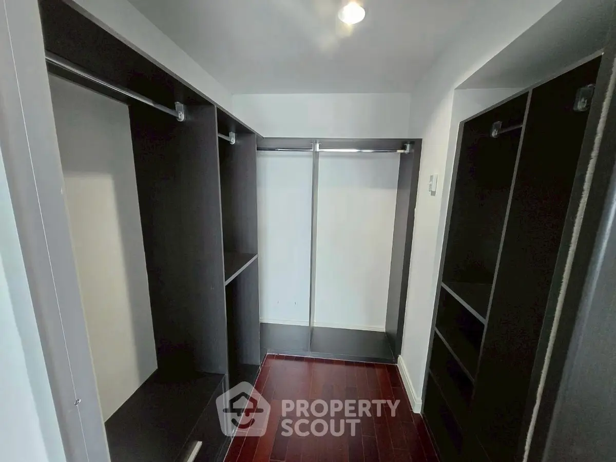 Spacious walk-in closet with dark wood shelving and ample storage space.