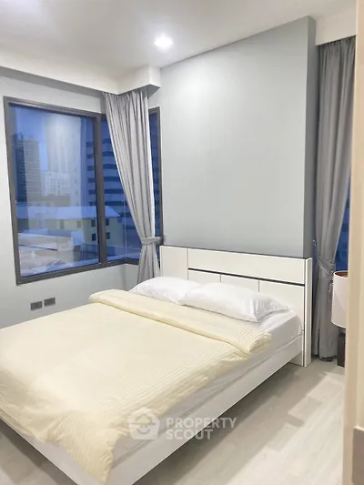Modern bedroom with large windows and city view in a high-rise apartment.